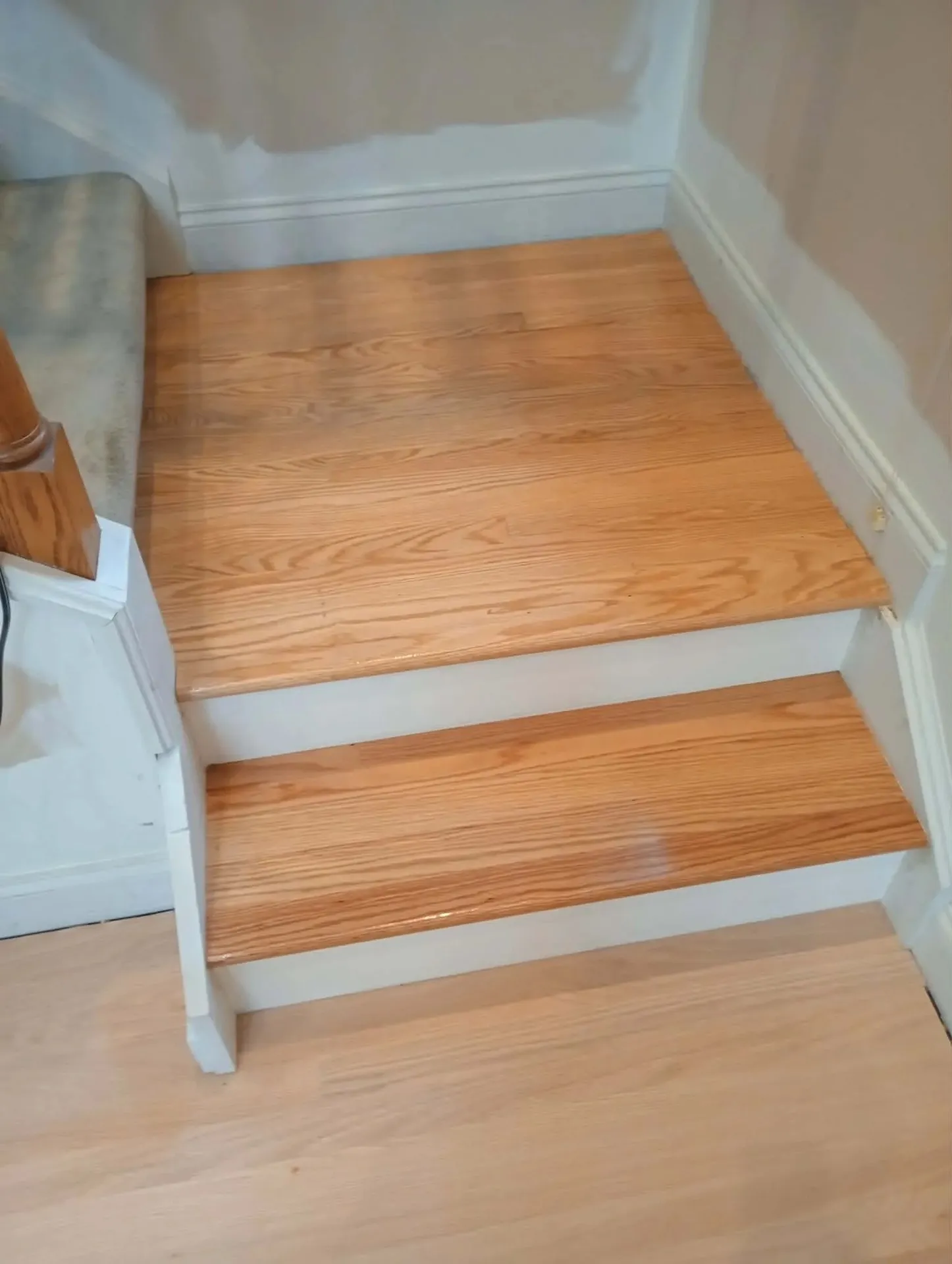 Freshly finished red oak stair treads with white risers leading down to a light hardwood floor