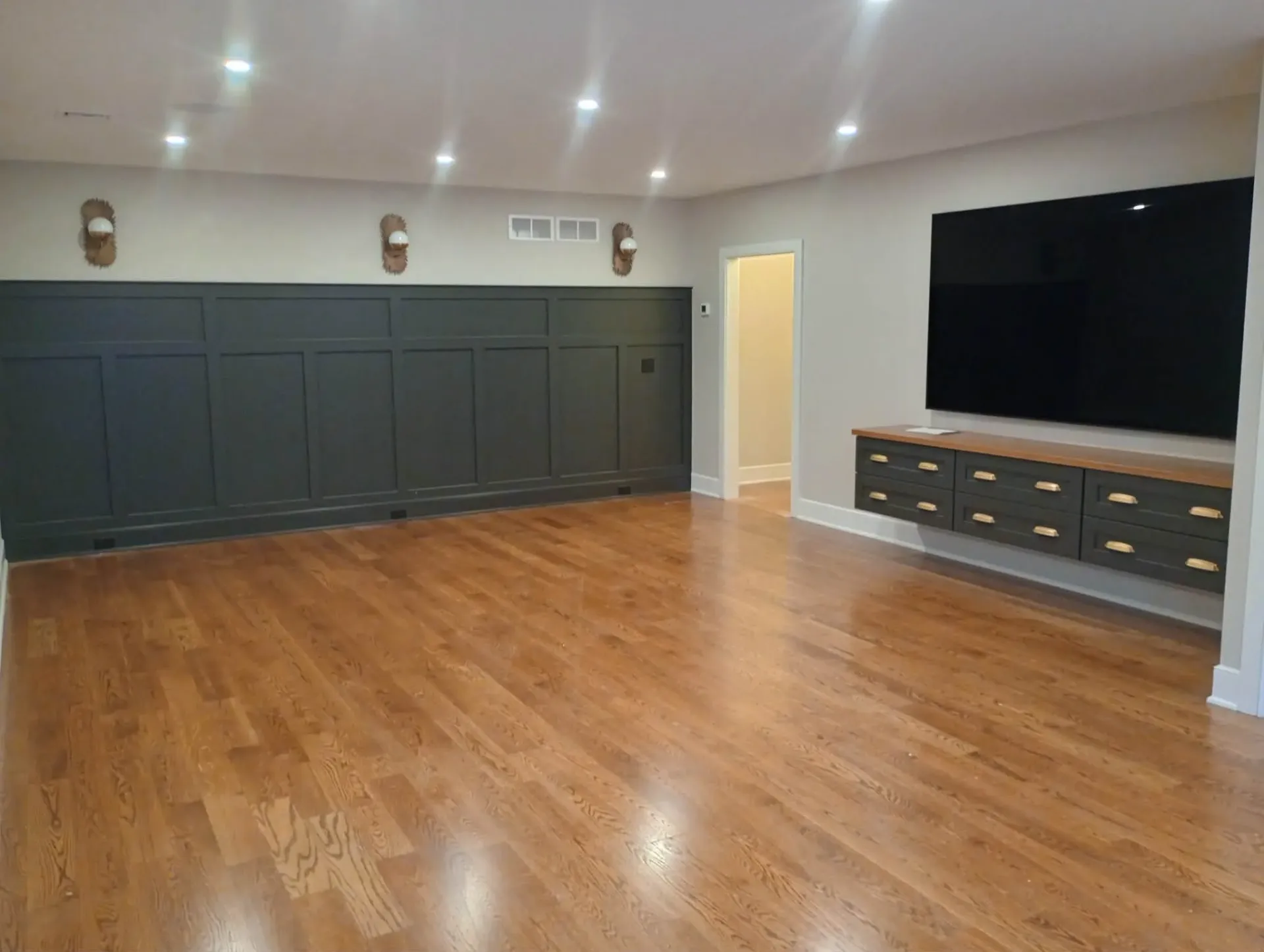 Finished basement family room with gleaming oak hardwood floor and dark paneled wainscoting